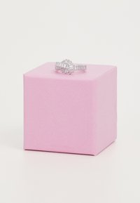 Anello d'argento con un design floreale che presenta varie gemme tagliate, poggiato su una scatola regalo rosa con texture.