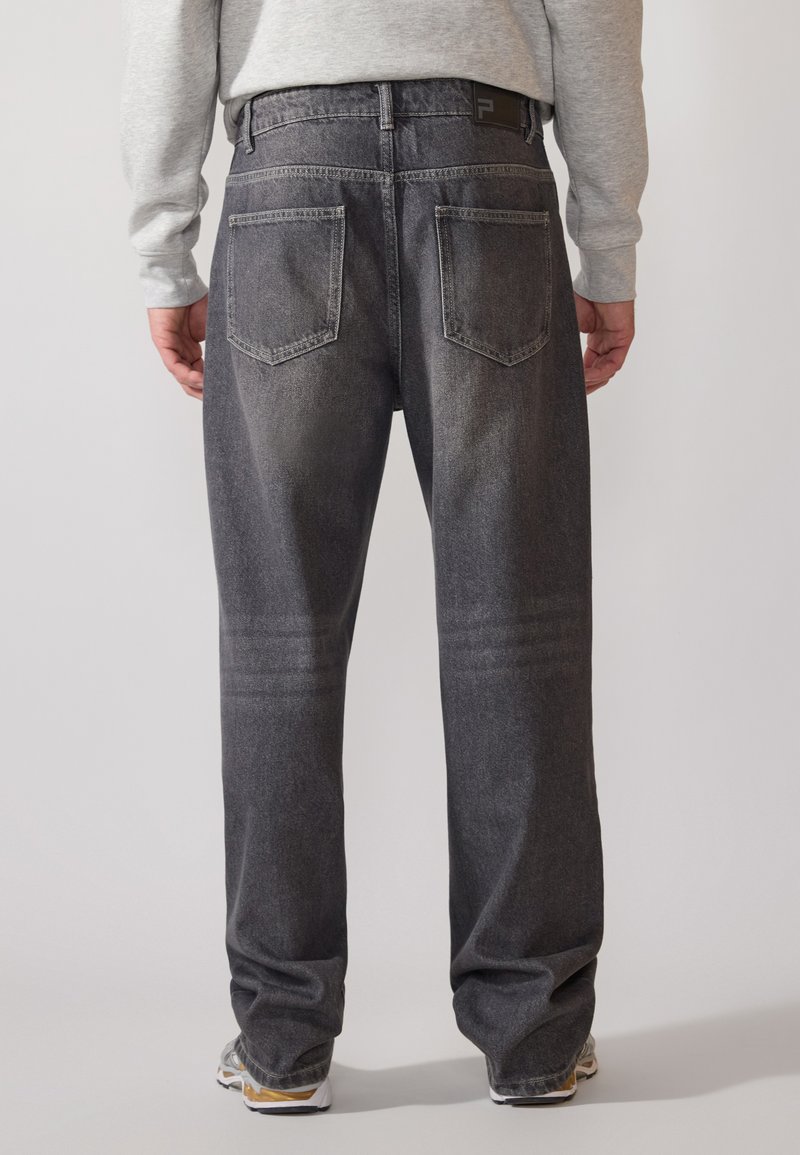 Ciemnoszare dżinsy o luźnym kroju, z tylnymi kieszeniami, widocznymi szwami i markowym pasem. Zwężająca się nogawka.