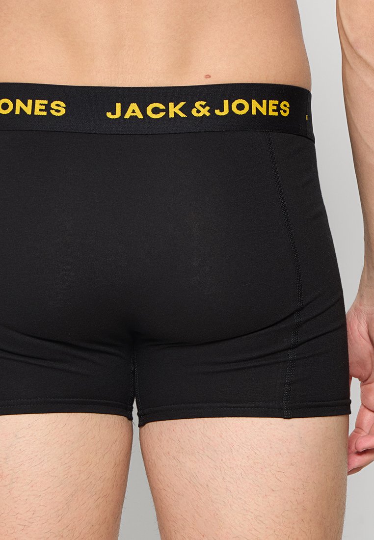 Boxer negros con un logotipo amarillo "JACK & JONES" en la cinturilla. Tejido suave con un diseño ajustado y detalles de costura visibles.