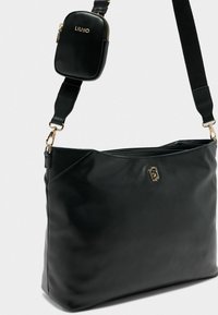 Borsa a spalla in pelle nera con accessori dorati, una mini busta con zip attaccata e texture liscia; presenta un ampio scomparto principale.