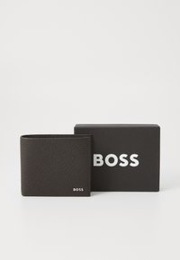 Čierna kožená peňaženka s textúrou štrkového vzoru, so jemným strieborným logom "BOSS" na dolnej strane vpredu, vedľa čiernej krabičky s bielym písaním.