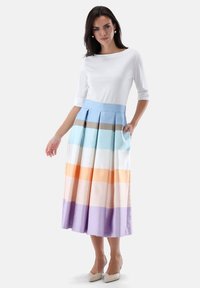 Weißes Top mit dreiviertelärmel, kombiniert mit einem plissierten, mehrfarbigen Rock mit horizontalen Streifen in Pastelltönen von Blau, Orange und Lila.