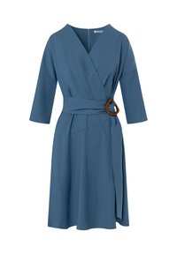Robe portefeuille bleue en tissu doux avec un décolleté en V, des manches trois-quarts et un accent en anneau en bois à la taille. Jupe fluide avec une fente sur le côté.
