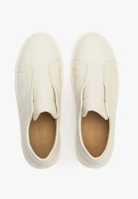 Kremowe sneakersy wsuwane o gładkim wykończeniu, z elastycznymi paskami na górze i jasnobrązowymi wkładkami. Dyskretne logo po boku.
