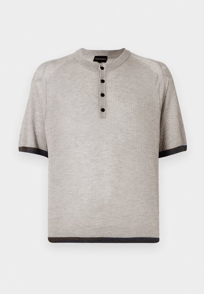 Lühikeste varrukatega heledast hallist henley-särgist, millel on ribiline tekstuur, kolm tumedat nuppu ja kontrastne tumedat ääreline kaelas ja varrukatel.