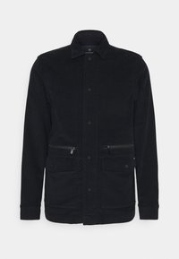 Chaqueta de pana en azul marino oscuro, con cierre de botones en el frente, dos bolsillos en el pecho con cremallera y un cuello clásico con acabado texturizado.