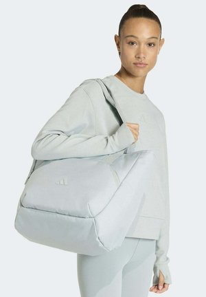 Light gray sports bag made from padded fabric, featuring a large zippered compartment and an adjustable shoulder strap. Logo is displayed subtly.