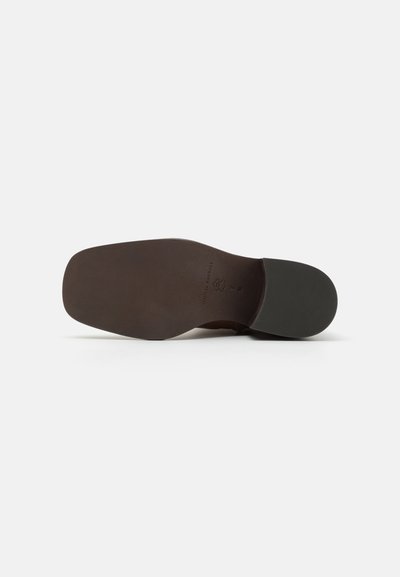 Semelle de chaussure en cuir marron avec une surface lisse et une section en caoutchouc antidérapante. Présente un logo en relief près du talon et un design de bout arrondi.