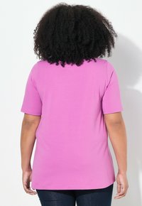 T-shirt a maniche corte di colore rosa brillante, realizzato in tessuto morbido. Design a taglio dritto con scollatura rotonda e superficie liscia.