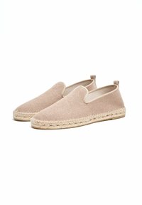 Beige instapschoenen met een bovenwerk van textuurstof, elastische zijkanten en een geweven juten zool. Ronde neus en minimalistisch ontwerp met subtiele accenten.
