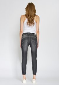 Tunnhudade mörkgrå jeans i denim, med medelhög midja, minimal noppor och två bakfickor med dekorativ sömnad.