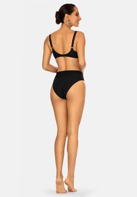 Czarny kostium kąpielowy w paski z dekoltem w serek i regulowanymi ramiączkami, z wysokimi majtkami zapewniającymi pewne dopasowanie. Gładka faktura.
