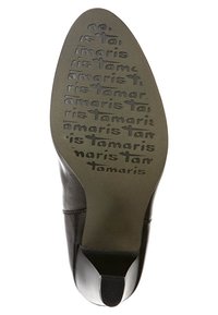 Suela de zapato de cuero negro con el nombre de la marca "Tamaris" grabado en repetición. Forma ligeramente puntiaguda y textura suave. Tacón plano.