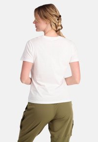 Witte t-shirt met korte mouwen van katoen, gezien van achteren. Gekomplementeerd met olijfgroene cargobroek met zijzakken.