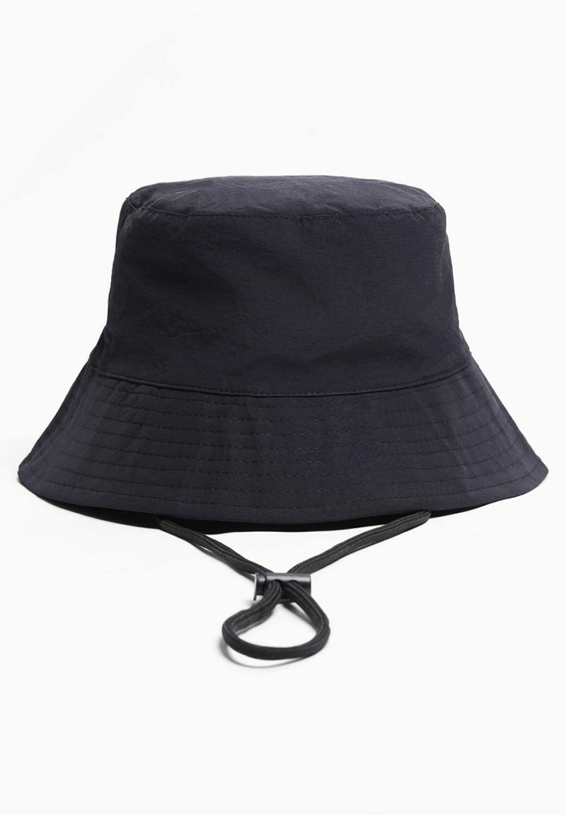 Gorra de cubo negra con ala ancha cosida y correa ajustable para la barbilla con regulador sobre fondo blanco.