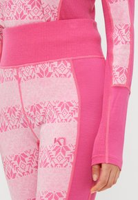 Roupas de desporto rosa com uma cintura canelada e padrões gráficos. Textura suave com vários tons de rosa e um pequeno detalhe de logotipo.