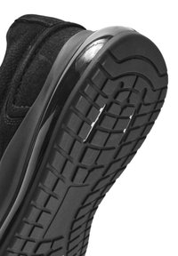 Sneaker nera con tomaia testurizzata e suola liscia. Presenta un motivo di battistrada pronunciato con una tasca d'aria visibile per l'ammortizzazione.