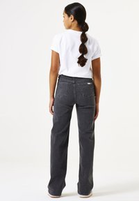 Jeans grises de cintura alta con corte recto, cinco bolsillos y un sutil detalle de costura, combinados con una camiseta blanca sencilla.