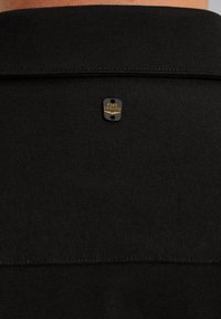 Czarna koszula z teksturowanej tkaniny, z małą metalową metką wytłoczoną napisem "PME LEGEND" na tylnym kołnierzyku. Czysty design i wykończenie.