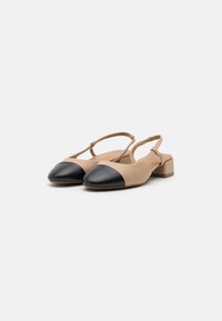 Beige nahast slingback-kingi musta kapiga, plokk-kontsaga ja reguleeritava rihmaga. Sile tekstuur ja minimalistlik disain.