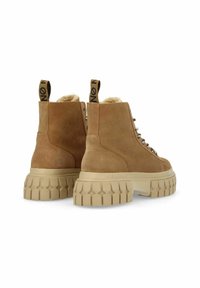 Stivaletti alla caviglia in suede beige con suola chunky beige, caratterizzati da un motivo testurizzato, occhielli in metallo e linguette nere sui talloni.
