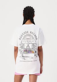 Camiseta de algodón blanca con un dibujo en línea negro de una heladería, con bolas de helado de colores en una vitrina y el texto "ELLESSE GELATO."
