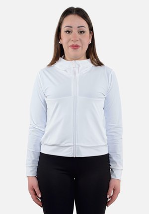 Giacca bianca con zip realizzata in tessuto liscio e leggero, con colletto alto e polsini a costine, abbinata a leggings neri.