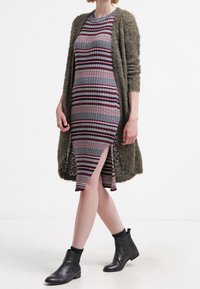 Jersey randig klänning i vinröd, grå och vit, tillsammans med en lång, fluffig olivgrön cardigan och svarta ankelskor med elastisk detalj.