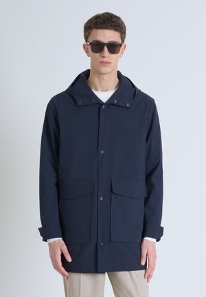 Giacca a vento blu navy realizzata in materiale resistente all'acqua, con cappuccio, grandi tasche frontali e chiusura con bottoni a pressione.
