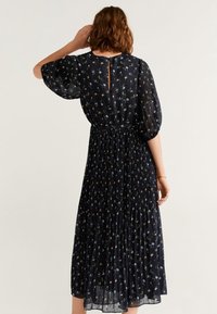 Robe navy à imprimé floral avec des manches courtes bouffantes, jupe plissée et un détail en clé à l'arrière. Tissu léger avec une silhouette fluide.