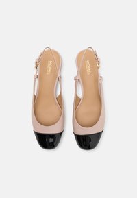 Ballerine slingback in pelle verniciata beige con punta in pelle verniciata nera, dotate di una fibbia dorata e un design liscio e minimalista.