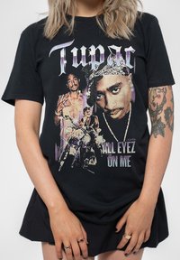 Black cotton T-shirt featuring a graphic print of Tupac, text "ALL EYEZ ON ME," and images in purple and white accents. Round neckline, short sleeves.