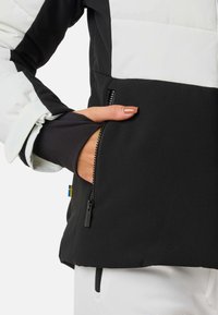 Giacca a vento imbottita con un design a blocchi di colore bianco e nero. Presenta una tasca con cerniera e un tessuto morbido e texture. Vestibilità aderente ai polsini.