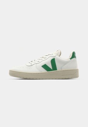 Sneaker in pelle bianca con dettagli verde, punta tonda e lavorazione perforata. Presenta una suola beige testurizzata e chiusura con lacci.