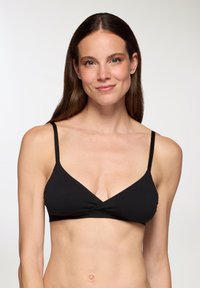 Bralette a triangolo nero con spalline sottili e regolabili, realizzato in cotone morbido, con un design incrociato sul davanti e una superficie liscia.