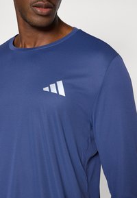 Μακρυμάνικο πουκάμισο σε ναυτικό μπλε χρώμα από ελαφρύ ύφασμα με ομαλή υφή και ανακλαστικό λογότυπο στη αριστερή πλευρά του στήθους.