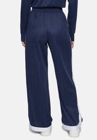Pantaloni a gamba larga a righe navy con cintura elastica, dettagli bianchi all'orlo e texture a coste, adatti per un abbigliamento casual.
