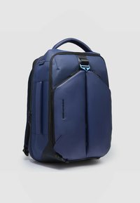 Zaino blu navy realizzato in tessuto resistente con un design elegante, caratterizzato da una silhouette strutturata, scomparti con cerniera e una maniglia superiore.