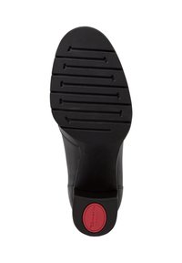 Semelle de chaussure noire avec des rainures horizontales pour la tenue et une insertion circulaire rouge au talon portant la mention "Tamaris Comfort."