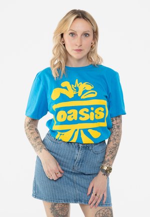 Blue cotton t-shirt with yellow "Oasis" graphic. Short sleeves, relaxed fit. Paired with a light blue denim skirt with vertical stripes.