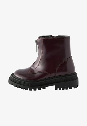 Burgundy patent leather ankle boot with a side zipper, rounded toe, and chunky black tread sole. Features visible stitching and a smooth finish.