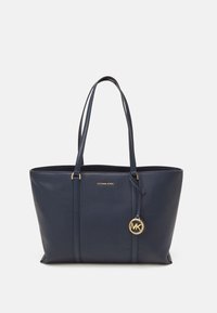 Sac fourre-tout en cuir navy à relief avec deux poignées, quincaillerie dorée et un charm MK proéminent attaché sur le côté.