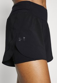 Mustat urheilushortsit korkealla vyötäröllä, sivuttaisviilto designilla, sileällä tekstuurilla ja Under Armour -logolla hillityssä tummassa sävyssä.