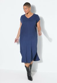 Marineblauwe V-hals, korte mouwen jurk met een rechte silhouet en zijsplitten; gecombineerd met zwarte studs enkellaarsjes.