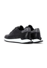 Sneakers in pelle nera con una texture liscia, accenti grigi e una suola intermedia bianca. Presentano dettagli perforati e una chiusura con lacci.