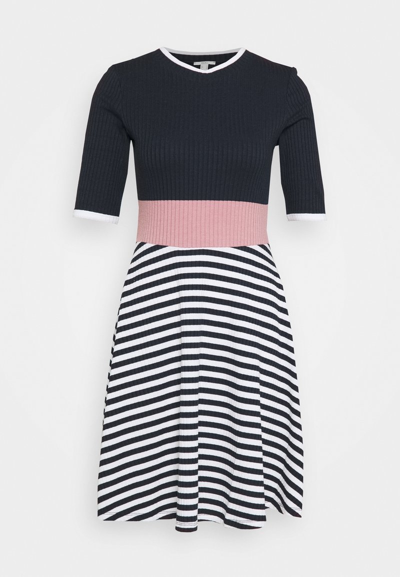 Robe longueur genou avec haut côtelé noir, ceinture rose, manches mi-longues et jupe rayée en diagonale noir et blanc.