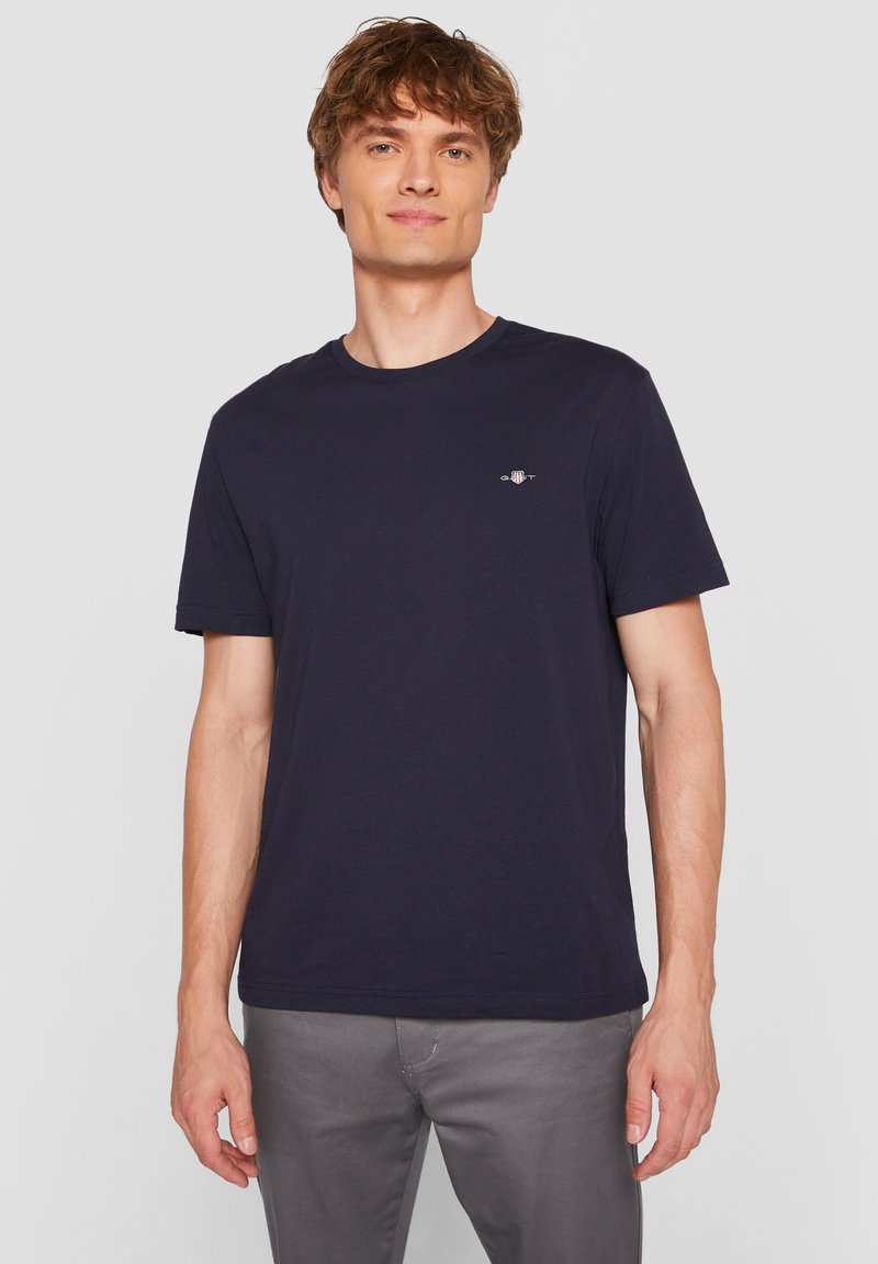 Granatowy bawełniany t-shirt z okrągłym dekoltem, krótkimi rękawami i małym logo na piersi. Miękka tekstura i regularny krój.