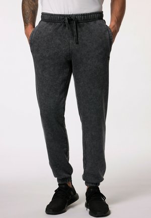 Joggers de felpa grises con una cintura elástica y cordón, bolsillos laterales y puños elásticos. Textura suave con un acabado ligeramente desgastado.