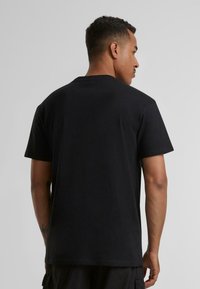 Black cotton t-shirt with a crew neck and short sleeves, featuring a smooth texture and a relaxed fit. No visible patterns or accents.