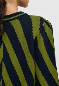 Pull en tricot présentant un motif de rayures diagonales vert et bleu marine, un col côtelé et des manches légèrement bouffantes avec un tissu texturé.
